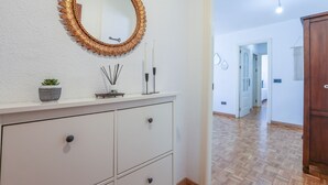 A hallway with a white wall, a wooden floor, a mirror with a golden frame, and a cabinet with drawers. - Mirador De Triana in Sevilla (Seville)