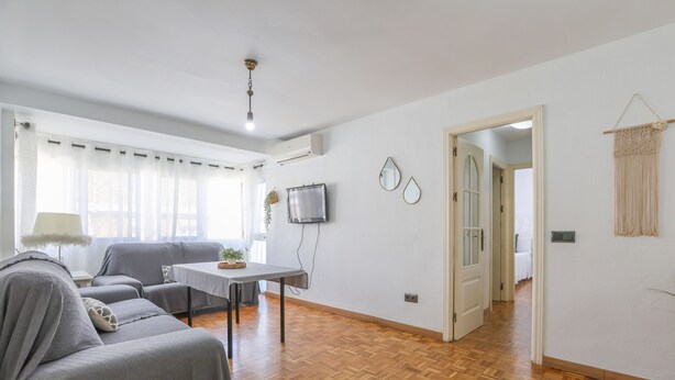 A spacious living room with a sofa, a table, and a TV. - Mirador De Triana in Sevilla (Seville)
