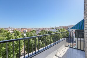 A balcony with a metal railing overlooking a cityscape with buildings and trees. - Mirador De Triana in Sevilla (Seville)