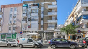 A multi-story building with balconies, a visible storefront, and parked cars. - Mirador De Triana in Sevilla (Seville)