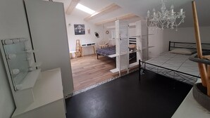 Un dormitorio moderno con una cama litera, un tocador con espejo e iluminación, un sillón colgante y una araña.