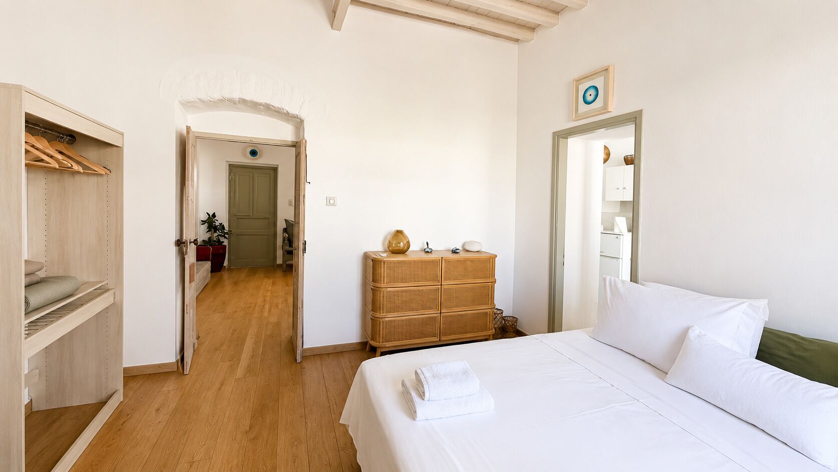 Una habitación de hotel con una cama, un armario, un tocador y una puerta que da a otra habitación.