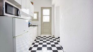 Eine kleine Küche mit Mikrowelle, Kühlschrank und einem Schachbrettmuster-Boden.