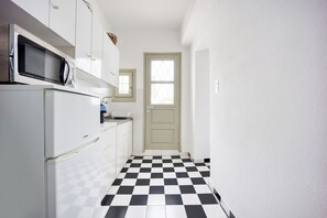 A compact kitchen with a microwave, refrigerator, and a checkered floor. - Folegandros Chora Bliss by Estia (Folegandros)