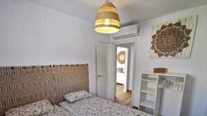 Une chambre avec un grand lit, un luminaire suspendu, une armoire et un élément décoratif mural.