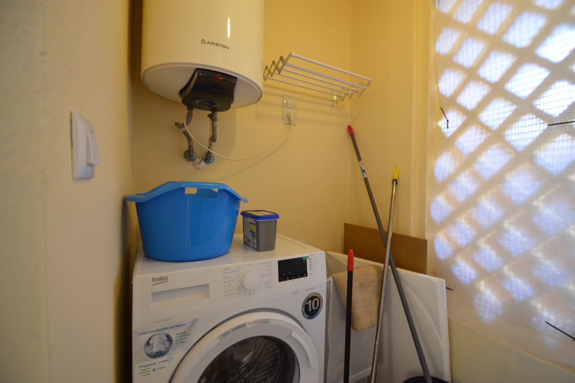 Un área de lavandería con lavadora, un lavabo azul y un calentador.