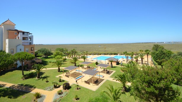 A resort with a pool area, palm trees, and a view of the ocean. - Las Marismas 71 - Two Bedroom Apartment, Sleeps 5 (Punta del moral)