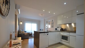 A modern kitchen with white cabinets, a central island, and a dining area with a sofa and table. - Las Marismas 71 - Two Bedroom Apartment, Sleeps 5 (Punta del moral)