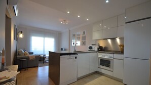 A modern kitchen with white cabinetry, a central island, a built-in oven, and a microwave. - Las Marismas 71 - Two Bedroom Apartment, Sleeps 5 (Punta del moral)