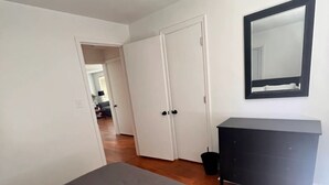 A bedroom with a bed, a dresser, a mirror, and a door leading to another room. - The Salon- 3 miles from WEC (Wilmington)