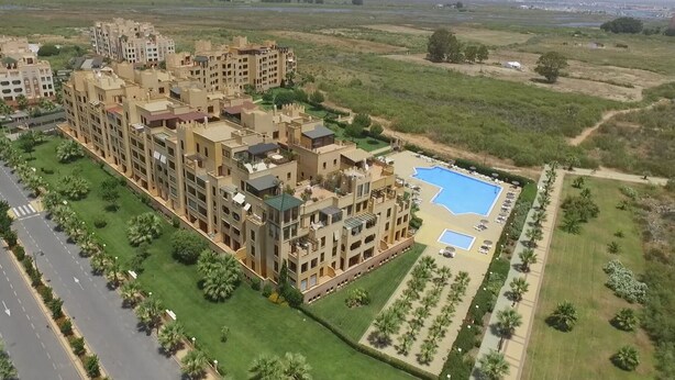 Een groot appartementencomplex met meerdere balkons en een zwembad.