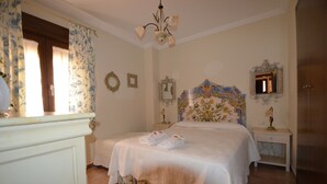 Een slaapkamer met een groot bed, een dressoir, een nachtkastje en een spiegel.