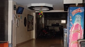 A spacious lobby with a tiled floor, a reception desk, a mounted TV, and a vending machine. - Hotel Jhonyky (Bucaramanga)