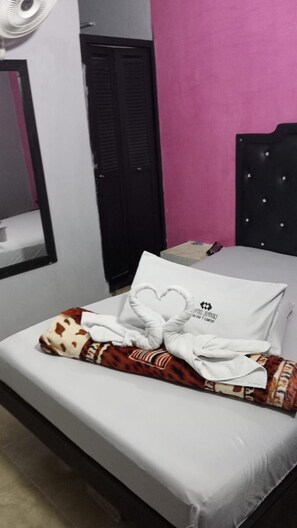 Ein Hotelzimmer mit einem Bett, einem schwarzen Kopfteil, einem weißen Kopfkissen mit einem Logo und einem Handtuch auf dem Bett.