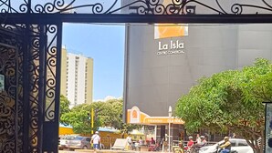 An entrance with decorative metalwork, a clear view of a commercial center with a sign reading "La Isla," and a street with pedestrians and vehicles. - Hotel Jhonyky (Bucaramanga)