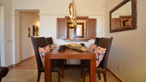 A dining area with a wooden table, wicker chairs, and a hanging light fixture. - Los Pelicanos 94 - Two Bedroom Apartment, Sleeps 5 (Punta del moral)