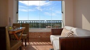 A balcony with a table and chairs, a sofa, and a large window offering a view of the landscape. - Los Pelicanos 94 - Two Bedroom Apartment, Sleeps 5 (Punta del moral)