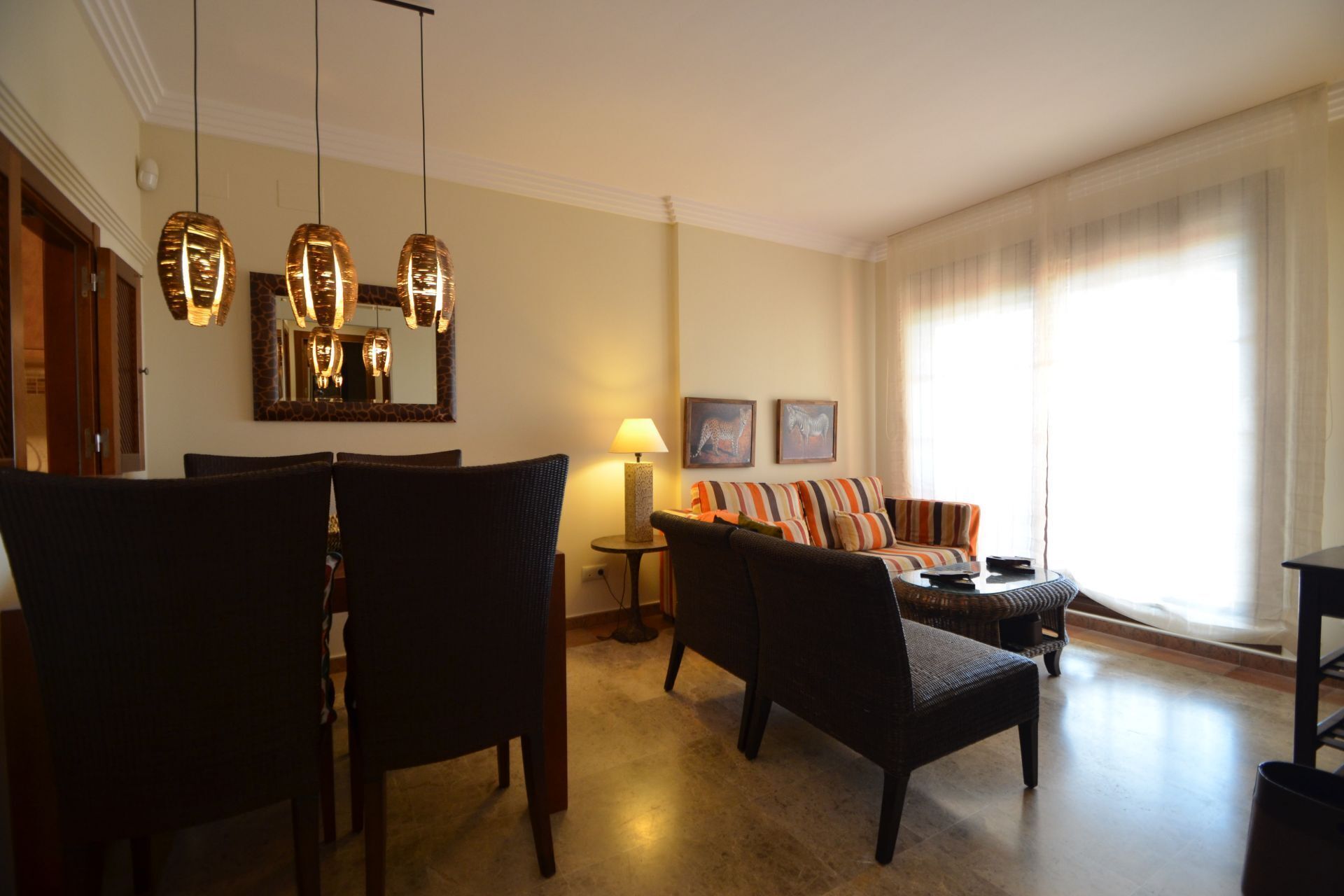 A living room with a dining area, featuring a sofa set, chairs, a coffee table, and pendant lighting.