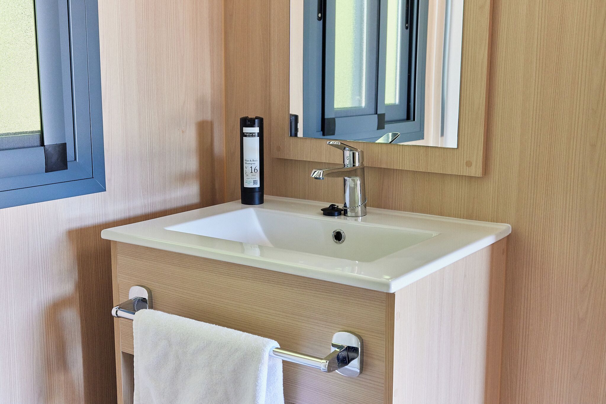 Un baño con un lavabo blanco, un espejo y un perchero para toallas.