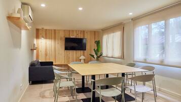 Una sala de reuniones moderna con un panel de pared de madera, un televisor de pantalla plana, una mesa grande y varias sillas.