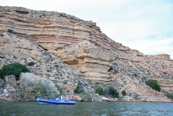 A boat on a river with a rocky cliff in the background.