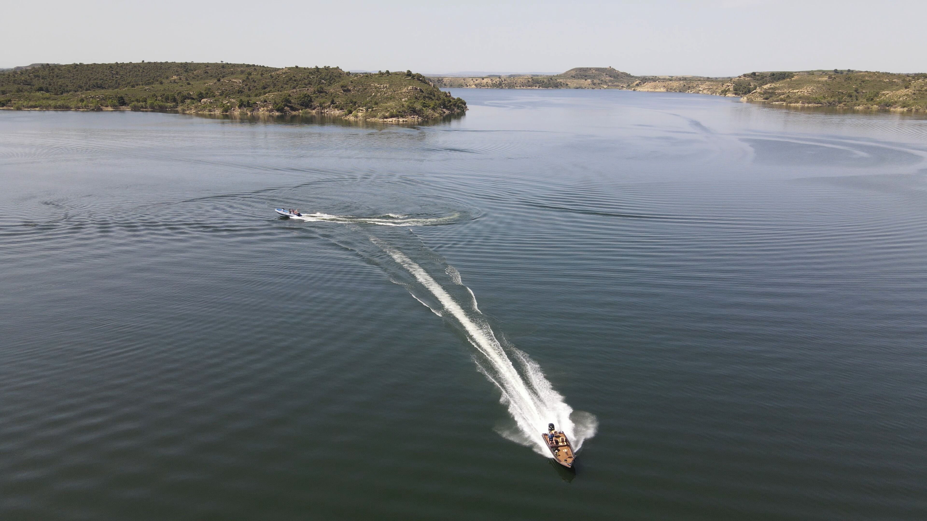 Un vaixell surant ràpidament per un llac tranquil, deixant una estela d'onades.