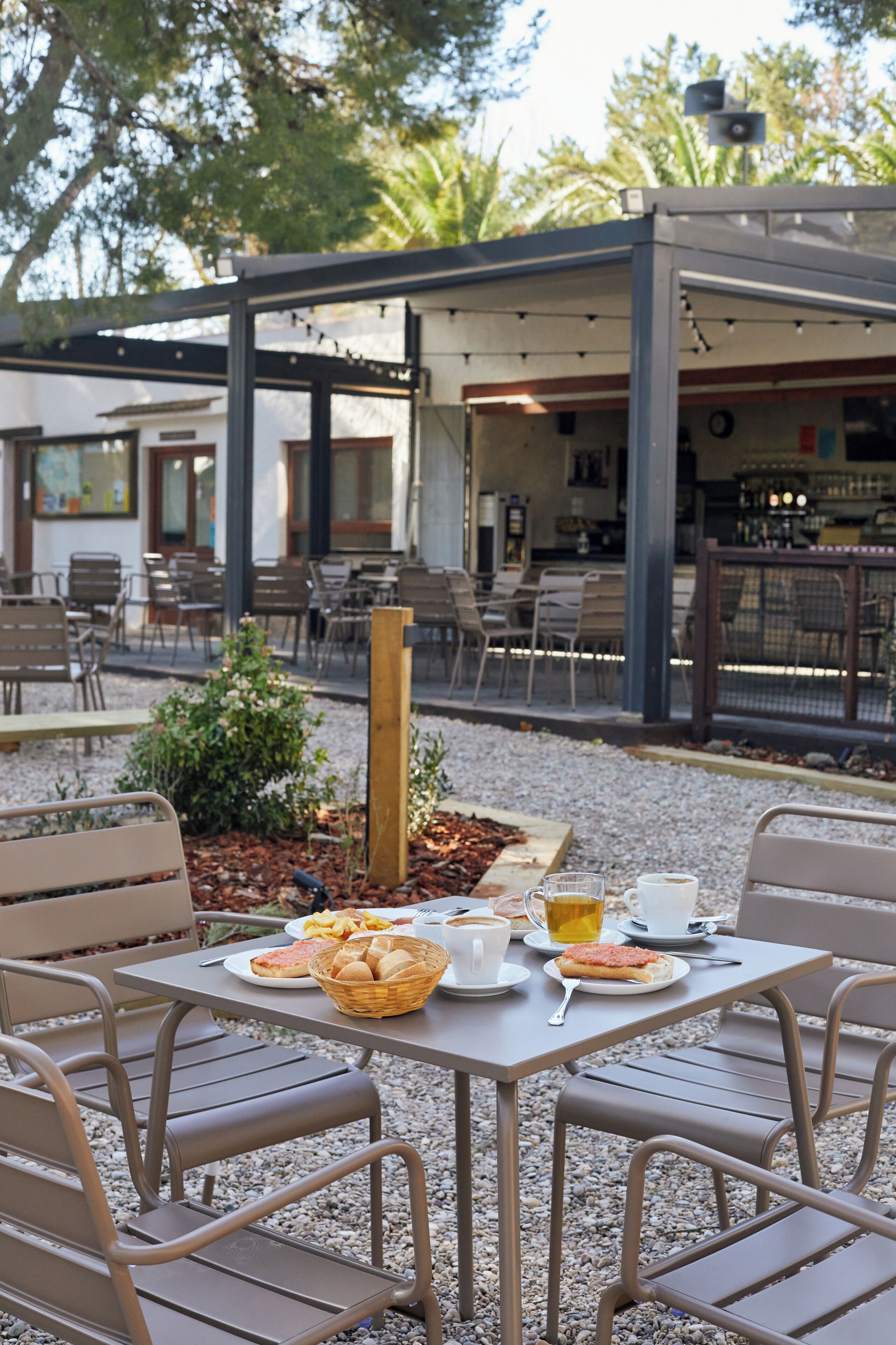 Un espace extérieur aménagé avec des tables et des chaises, un petit jardin et une terrasse couverte.