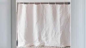 Un baño con una bañera blanca, una toalla colgada en la pared y suelo de baldosas.