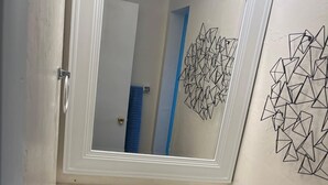 A bathroom with a white sink, a mirror above it, and a geometric wall decoration. - Cozy 2-bedroom apartment with AC and WiFi in welcoming Fort Myers (Fort Myers)