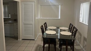 A dining area with a glass table, four chairs, and a ceiling fan. - Cozy 2-bedroom apartment with AC and WiFi in welcoming Fort Myers (Fort Myers)