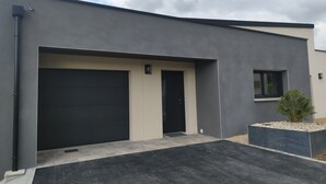 En moderne bygning med mørk facade, garage og et lille vindue.