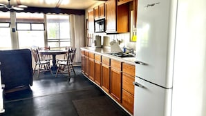 A kitchen with wooden cabinets, a white refrigerator, a dining table with chairs, and a ceiling fan.