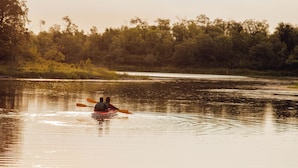 A calm river with a kayak and two people paddling.