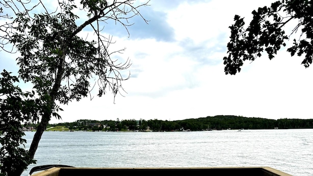 A wooden deck with two blue sofas and a white table, overlooking a body of water.