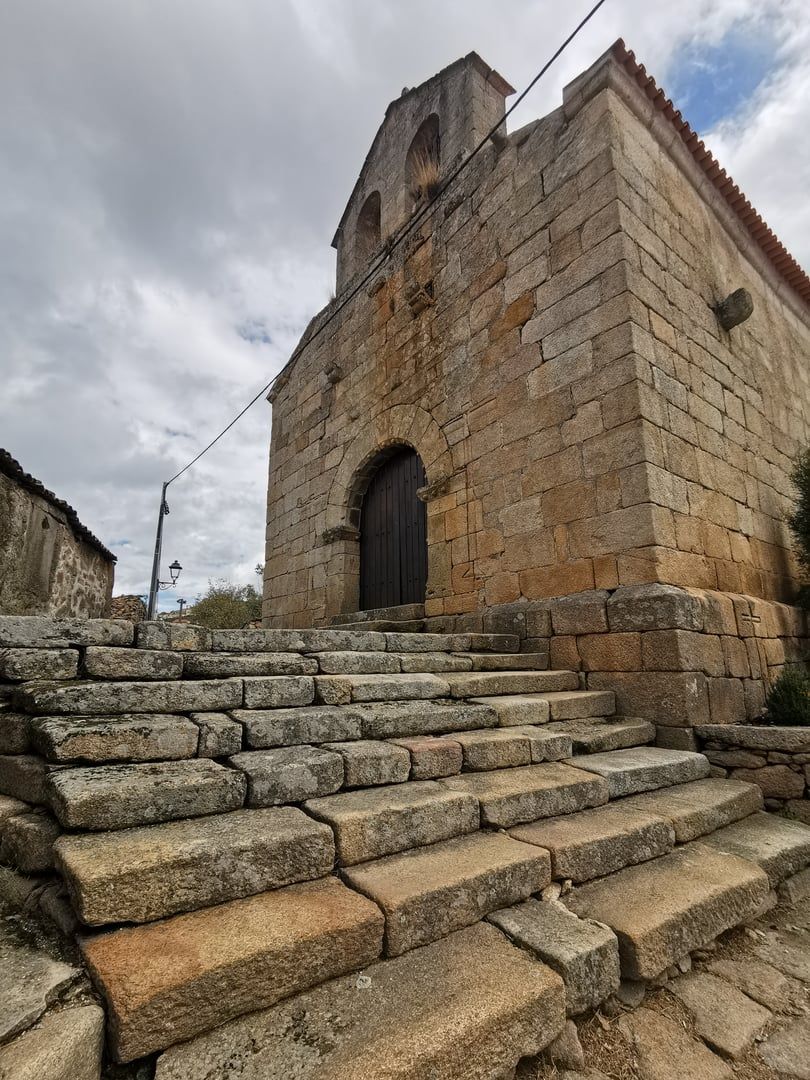 A stone building with a central arched doorway and a bell tower.