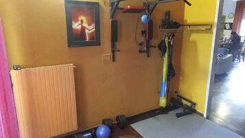 Une salle de sport à domicile équipée de matériel d’exercice, avec un radiateur et un tableau encadré accroché au mur.