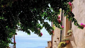 A narrow cobblestone alley with stone buildings, a small door, and potted plants. - Cinque Terre breakfast home with optional access to Pool, Sauna and Jacuzzi (SARZANA)