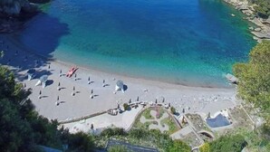 A coastal beach with clear blue waters, a sandy shore, and a few umbrellas. - Cinque Terre breakfast home with optional access to Pool, Sauna and Jacuzzi (SARZANA)