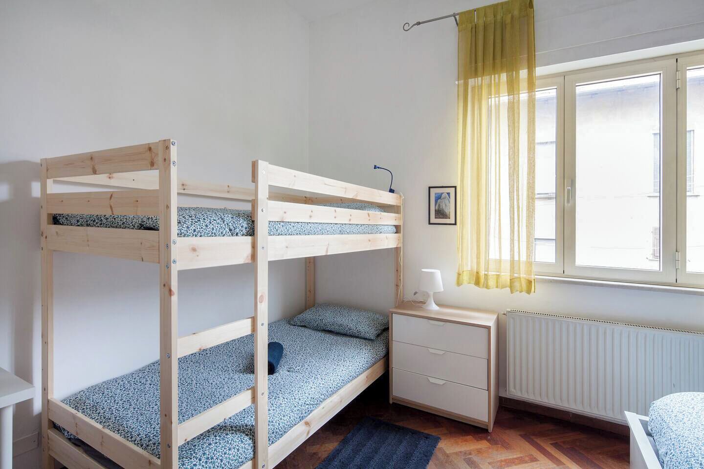 Una stanza con un letto a castello, una scrivania e una finestra con tende gialle.