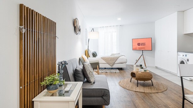 A modern, well-lit living room with a sofa, coffee table, and a TV mounted on the wall.