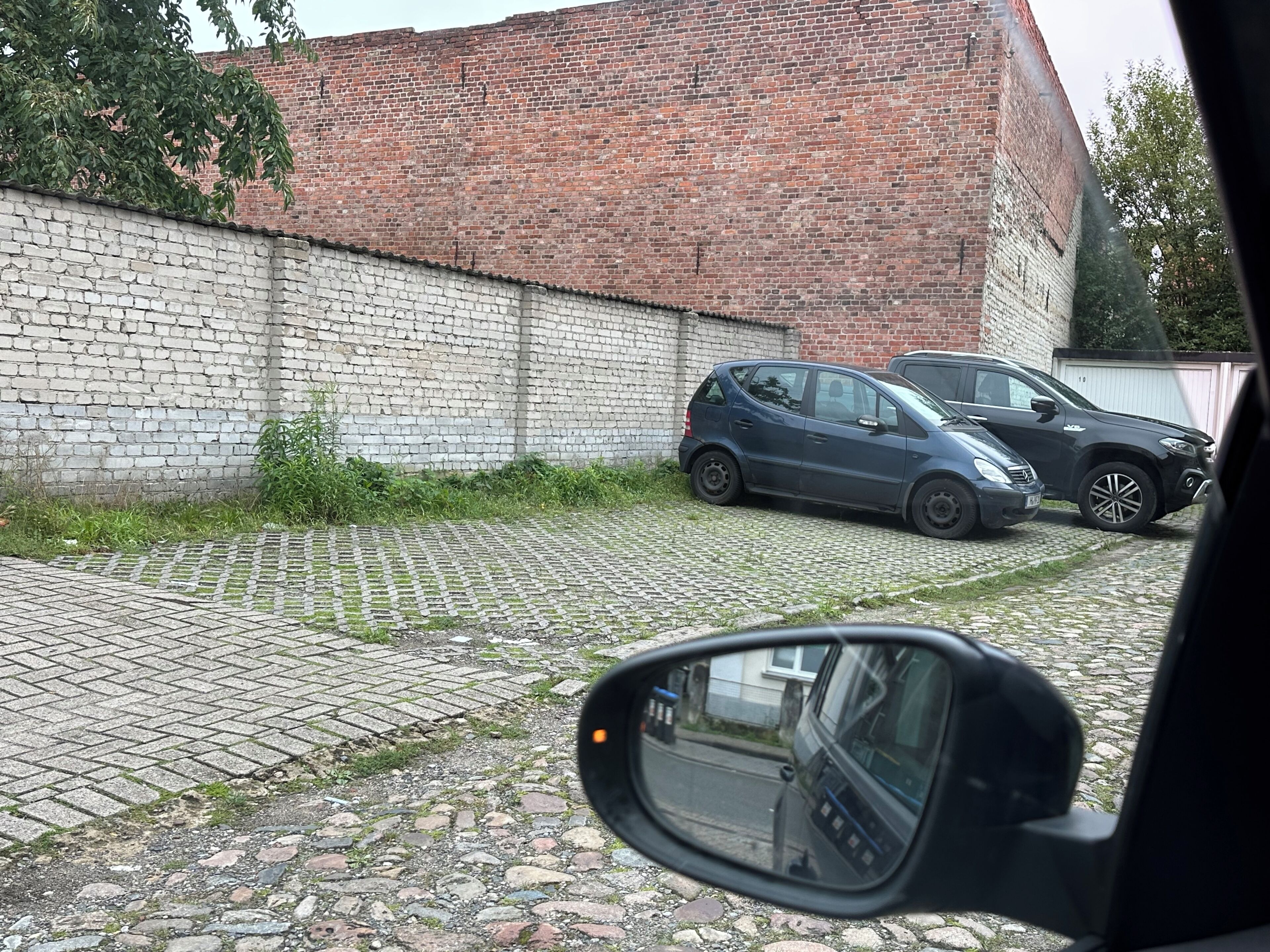 Un edificio de ladrillo con un camino pavimentado y coches estacionados.