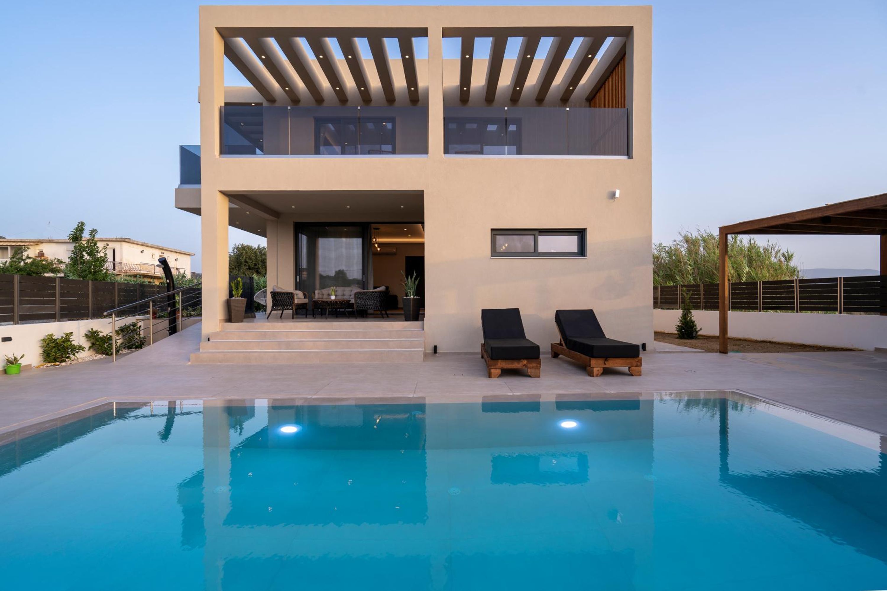 Une maison moderne à deux étages dotée d’une piscine, d’un espace salon extérieur et d’un patio couvert.