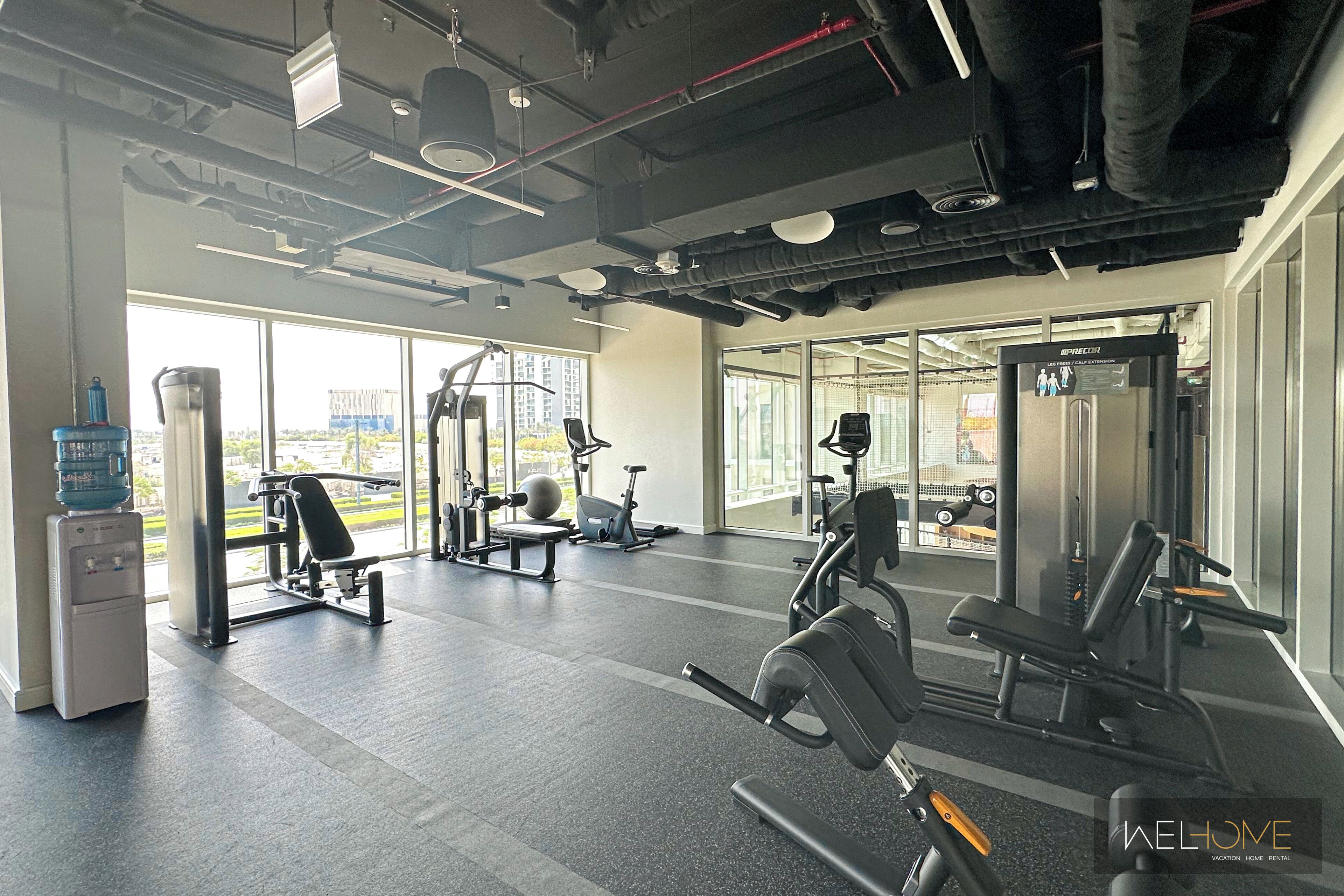 A gym with various exercise equipment, large windows, and a water dispenser.