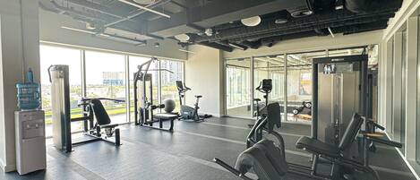 A gym with various exercise equipment, large windows, and a water dispenser.
