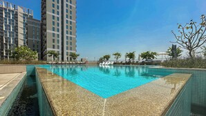 Une piscine à l’eau d’un bleu limpide, entourée d’une terrasse carrelée.