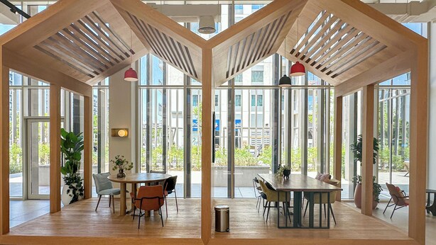 Un vaste espace intérieur doté de grandes fenêtres, de poutres en bois au plafond et d’une grande table à manger centrale entourée de chaises.