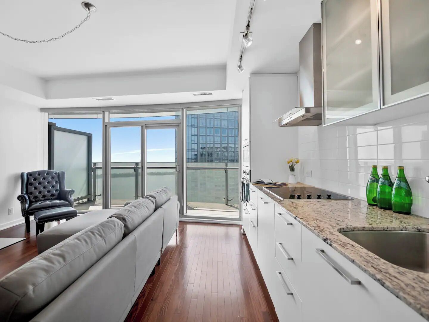 A modern kitchen with a large window, a grey sofa, and a dining area.