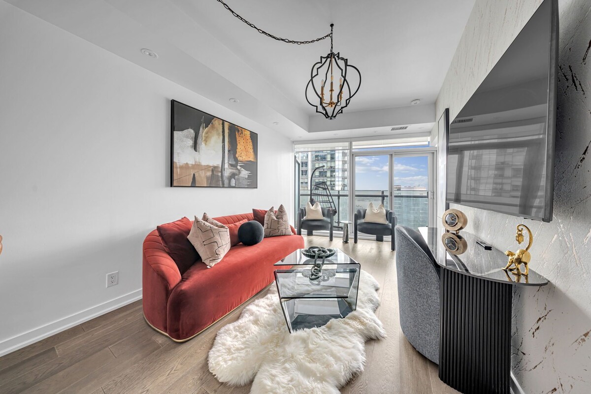 A modern living room with a red sofa, a glass coffee table, and a white furry rug.