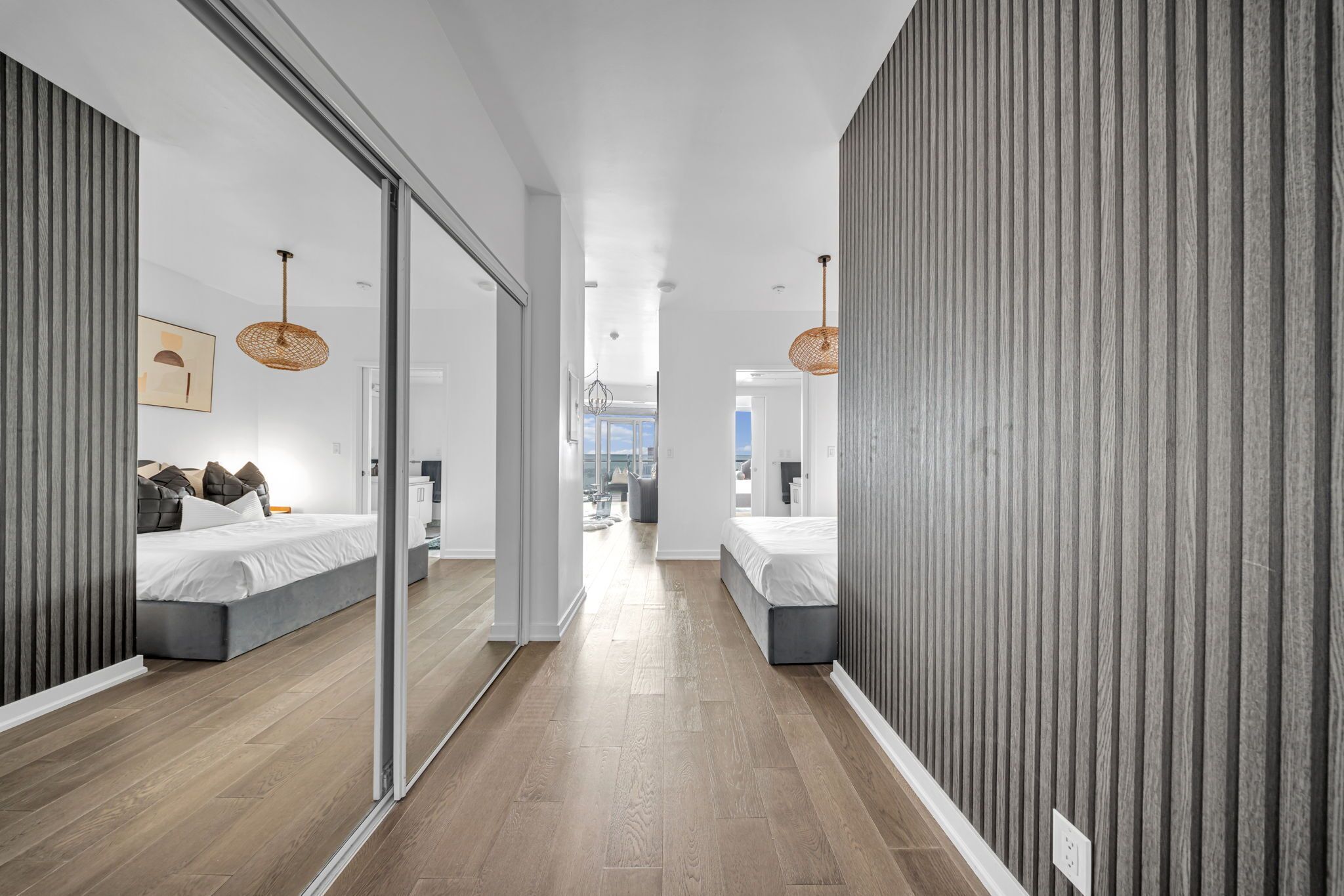 A modern hotel room with a large mirror, a bed, and a view of the city.
