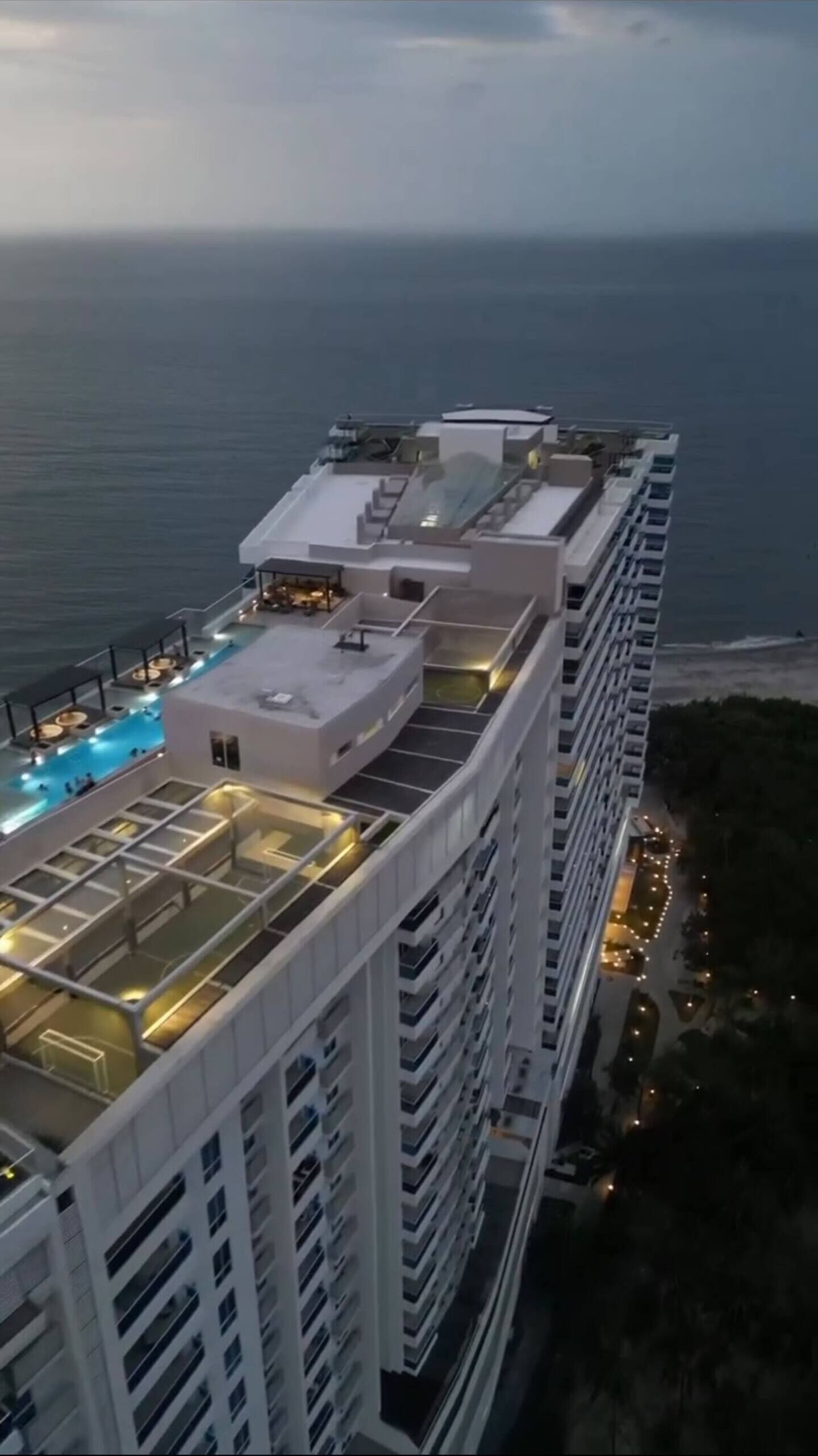 A high-rise hotel with a rooftop pool and multiple balconies.